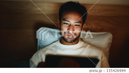 Scroll, night or man in bedroom with tablet, online reading or video browse on social media. Digital, dark or male person in house with tech, e book subscription or movie streaming in late evening. 135426994