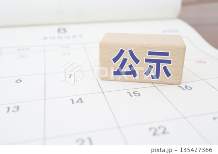 公示を示す青文字の木製ブロックとカレンダー背景。 135427366