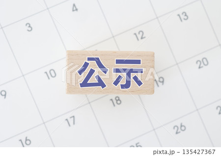 公示を示す青文字の木製ブロックとカレンダー背景。 135427367