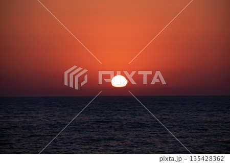 水平線に沈む変形した夕陽 135428362