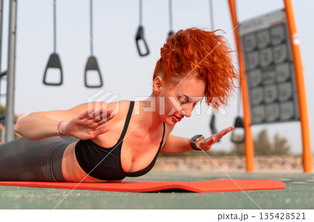 Fit redhead woman exercising on yoga mat at 135428521