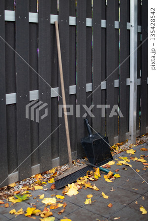Tools for autumn cleanup next to a wooden fence in a quiet outdoor space Tools for autumn cleanup next to a wooden fence in a quiet outdoor space 135428542