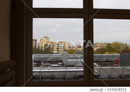 View of city rooftops from a building window on a cloudy day in autumn 135428551