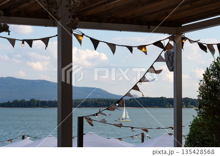 Scenic view of a sailboat gliding across a serene lake with festive decorations 135428568