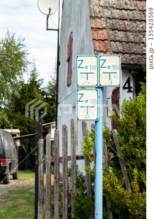 Traffic signs indicating speed limits next to a rural house on a quiet street  135428569