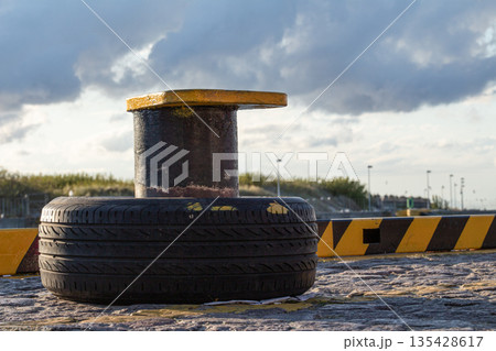 Docking equipment with a tire fender on the waterfront during sunset 135428617