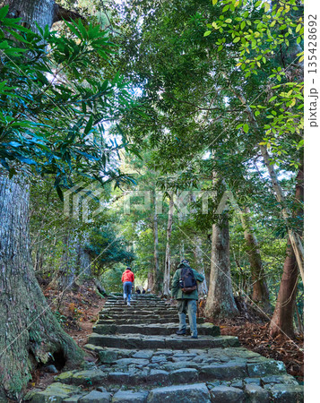 和歌山県の観光名所熊野古道の古い登山道の石畳道で歩く人々の外国人観光客の姿 135428692