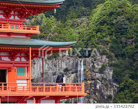 秋の和歌山県の観光名所那智勝浦の那智山青岸渡寺三重塔と那智の滝の風景を楽しむ観光客の姿 135428702