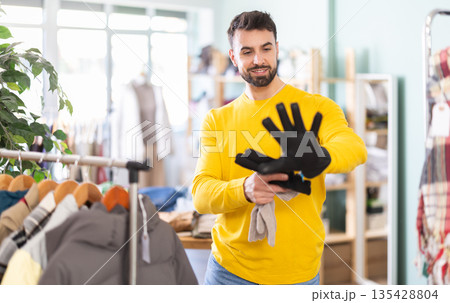 Man trying on gloves in a clothing store Man trying on gloves in a clothing store 135428804