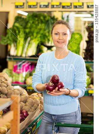 woman buy large onion in supermarket 135428887