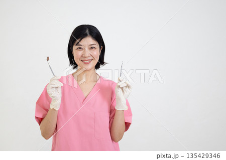 歯科用の器具を持って微笑むスクラブを着た女性 歯科用の器具を持って微笑むスクラブを着た女性 135429346