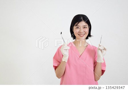 歯科用の器具を持って微笑むスクラブを着た女性 135429347