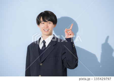水色背景で男子高生のカメラ目線の上半身の指差しのポイントでオススメ 受験勉強や進路などのイメージ 水色背景で男子高生のカメラ目線の上半身の指差しのポイントでオススメ 受験勉強や進路などのイメージ 135429797