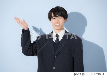 水色背景で男子高生のカメラ目線の上半身のこちらや案内の紹介オススメポーズ　受験勉強や進路 135429801