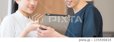 タブレットを見ながら説明する医療スタッフのチームワーク 看護師の申し送り5w1hに注意しよう 顔無し タブレットを見ながら説明する医療スタッフのチームワーク 看護師の申し送り5w1hに注意しよう 顔無し 135430814