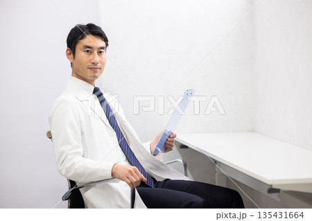 カルテを手に微笑む白衣を着た男性医師 135431664