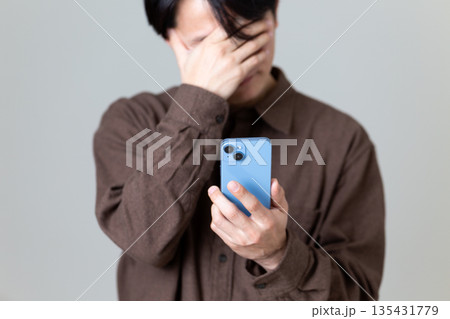 スマホを見て悩むミドル男性 スマホを見て悩むミドル男性 135431779