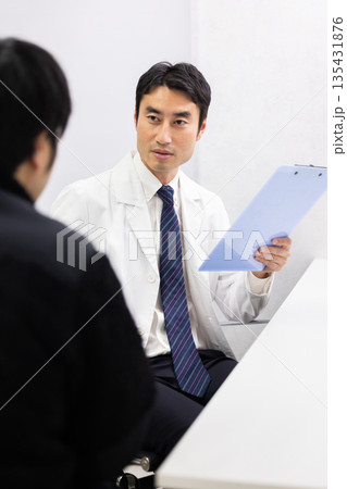 男性患者の診察をする白衣姿の男性医師 男性患者の診察をする白衣姿の男性医師 135431876