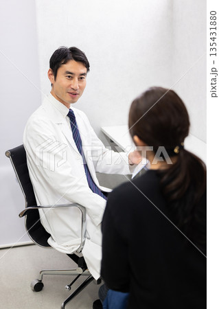 女性患者の診察をする白衣姿の男性医師 135431880