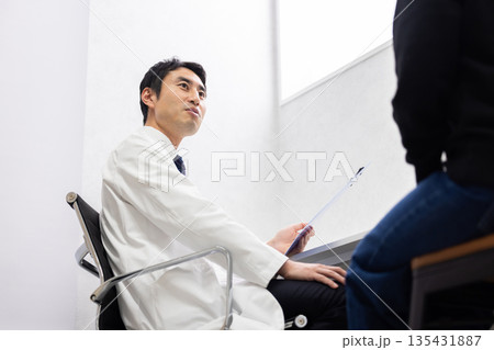 女性患者の診察をする白衣姿の男性医師 135431887