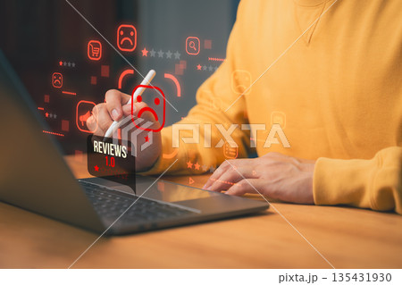 Negative online review concept showing a person using laptop with low rating icon and sad face, representing poor customer feedback, product dissatisfaction, digital reputation management issues. 135431930