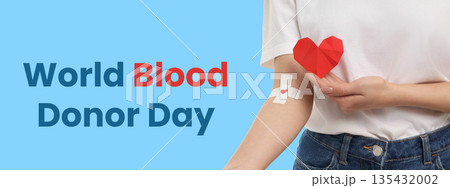 Hand holding origami heart next to a bandage on arm 135432002