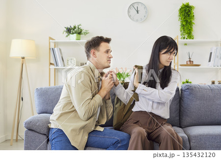 Desperate man sits beside a woman and begs her to stay, breakup after quarrel. 135432120