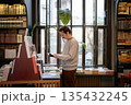 Mindful man choosing bestselling books in bookstore surrounded by shelves filled with publications. 135432245