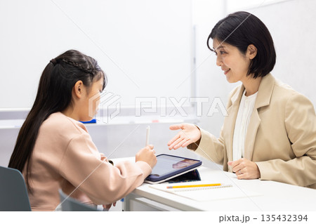 小学生に勉強を教える塾講師の女性 小学生に勉強を教える塾講師の女性 135432394