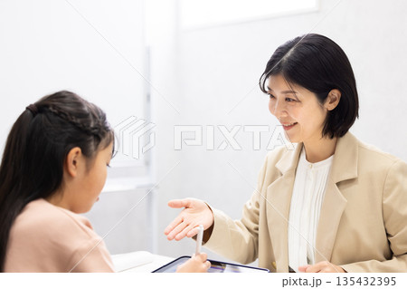 小学生に勉強を教える塾講師の女性 小学生に勉強を教える塾講師の女性 135432395