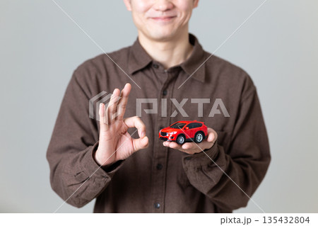 自動車の模型を持って丸サインをするミドル男性 自動車の模型を持って丸サインをするミドル男性 135432804