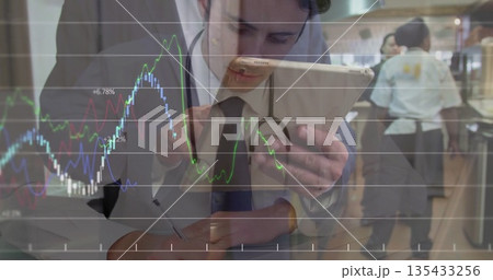 Reviewing tablet doctor in lab coat, stethoscope in kitchen with chefs showing overlaid line graphs 135433256