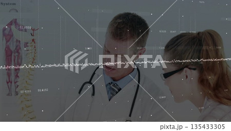 Two medical professionals examining spine model and pointing in consultation room Two medical professionals examining spine model and pointing in consultation room 135433305