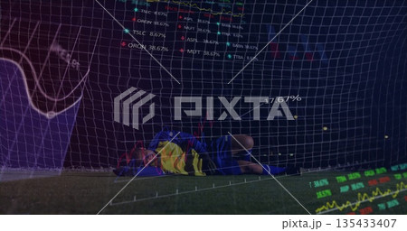 Diving goalkeeper wearing blue kit lying on turf near net at stadium, with digital overlay 135433407