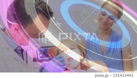 Examining dentist wearing mask and gloves inspecting girl wearing bib in dental chair, with mirror 135433491