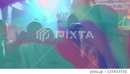 Raising fan wearing wide-brimmed hat making rock sign in light beams at concert venue, copy space 135433550