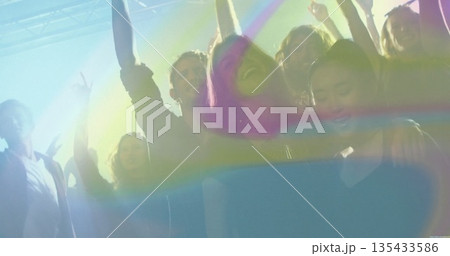Dancing six friends cheering under club lights, with overhead lighting rig and haze machine effects 135433586