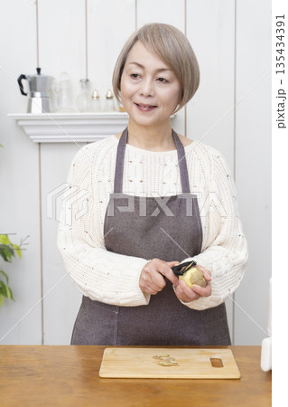 ノンフライヤーでおやつのポテトチップスを作るシニア女性 135434391