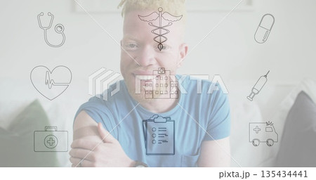 Smiling man in t shirt with wristwatch touching arm on sofa at home, floating medical icons Smiling man in t shirt with wristwatch touching arm on sofa at home, floating medical icons 135434441