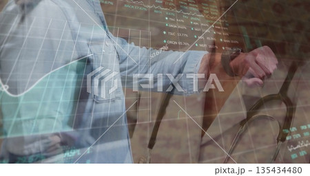 Checking smartwatch, clinician wearing denim shirt and stethoscope in clinic with financial charts Checking smartwatch, clinician wearing denim shirt and stethoscope in clinic with financial charts 135434480