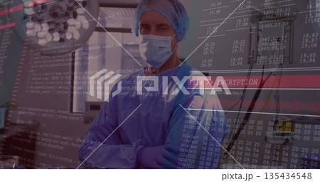Standing cross-armed surgeon wearing gown in procedure room, with surgical light and code overlay Standing cross-armed surgeon wearing gown in procedure room, with surgical light and code overlay 135434548