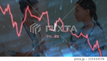 Two nurses in scrubs with stethoscopes discussing red data graph 70 135434576