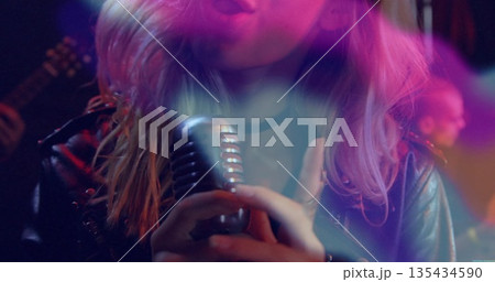 Singing singer wearing leather jacket gripping vintage mic onstage with electric guitar lights Singing singer wearing leather jacket gripping vintage mic onstage with electric guitar lights 135434590