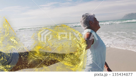Holding senior woman's hand behind on sandy beach with ocean waves, golden swirl effect, copy space Holding senior woman's hand behind on sandy beach with ocean waves, golden swirl effect, copy space 135434877