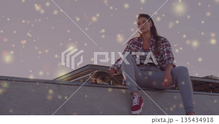 Sitting skateboarder wearing sportswear with skateboard on skatepark ramp edge and rail, copy space 135434918