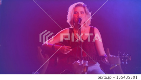 Playing acoustic guitar, teen musician singing into mic on stage, with stage lights, beer glass 135435501