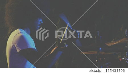 Indian percussionist wearing white t-shirt playing cabasa shaker and cymbals on stage, copy space 135435506