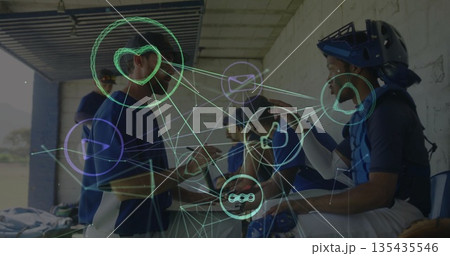Huddling coach and baseball players planning in dugout, with bats catcher's gear and social icons 135435546