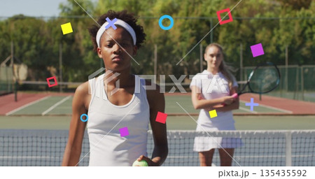 Preparing African American player in tennis dress holding ball near net on hard court, with rackets 135435592
