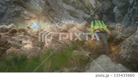 Hiker navigating gorge wearing green jacket harness belt backpack boots jagged rocks, copy space Hiker navigating gorge wearing green jacket harness belt backpack boots jagged rocks, copy space 135435660